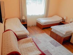 Zimmer mit 2 Betten, einem Sofa und einem Fenster in der Unterkunft Горный дом ЛЕС и ГОРЫ in Karakol