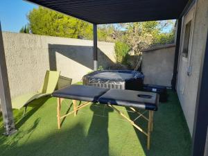 a patio with a bed and a table and chairs at Single storey 40m² bordering pine forest and spa in Noves