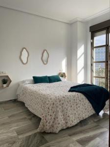 1 dormitorio blanco con 1 cama grande y 2 espejos en Apartamento turístico La Joya, en Huelva