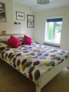 1 dormitorio con 1 cama grande con almohadas rosas en Charming Kintbury Cottage, en Kintbury