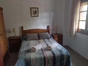 a bedroom with a bed with two towels on it at Casa el Pino in Cortes de la Frontera