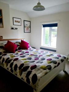 a bedroom with a large bed with red pillows at Charming Kintbury Cottage in Kintbury