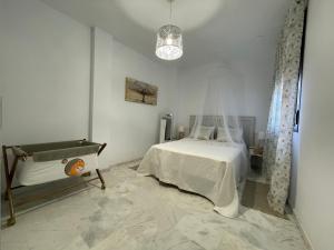 a white bedroom with a bed and a pendant light at El Callejón del Molino in Lucena