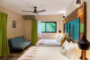 a bedroom with two beds and a blue couch at Aldea Coba An Escape Boutique Experience in Coba