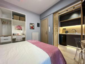 ein Schlafzimmer mit einem Bett und einem Waschbecken sowie eine Küche in der Unterkunft Purple studio in Thessaloniki