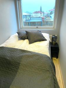 a bed with pillows in a room with a window at Lovely apartment with hot tub access in Akureyri