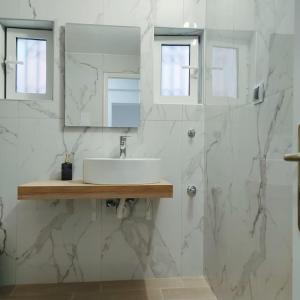 uma casa de banho branca com um lavatório e um espelho em Dream Apartment Ioannina em Ioannina