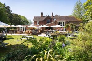 a garden with tables and umbrellas in front of a house at Charming Kintbury Cottage in Kintbury