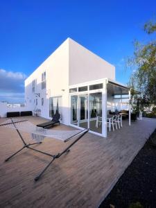 Azur Arts Lanzarote Lofts في تيناجون: مبنى أبيض مع طاولات وكراسي على سطح السفينة