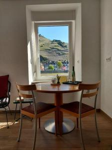 a table and chairs in a room with a window at Moselliebe Zell in Zell an der Mosel