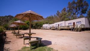 een groep tafels en paraplu's in het vuil bij cabañas laguna de zapallar maitencillo in Zapallar