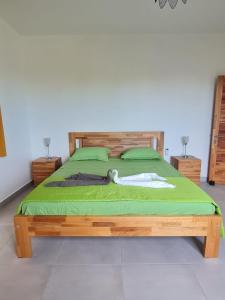 a bedroom with a wooden bed with green sheets at MoonLight in Pointe aux Piments