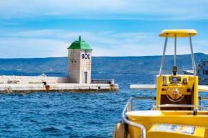 a yellow boat in the water next to a lighthouse at Apartments Villa Azzurra Bol in Bol