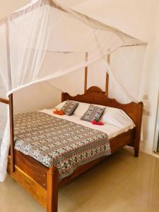 Ladha ya Zanzibar Boutique Guesthouse في جامبياني: غرفة نوم بسرير خشبي مع مظلة