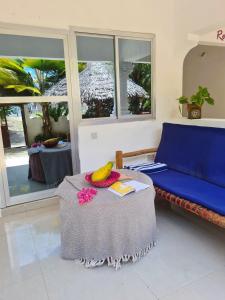 Ladha ya Zanzibar Boutique Guesthouse في جامبياني: غرفة معيشة مع طاولة وأريكة زرقاء