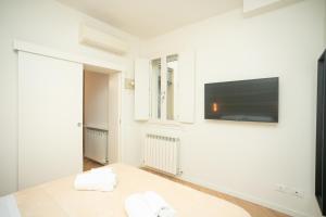 Habitación blanca con TV de pantalla plana en la pared en Modena Centro Junior Suite, en Módena