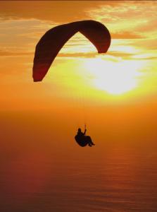 Eine Person reitet mit einem Fallschirm über den Ozean in der Unterkunft Beautiful View 2 - Arco da Calheta - Ilha da Madeira in Arco da Calheta