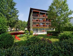 un grand immeuble avec un parasol dans une cour dans l'établissement Thermen-Hotel Rottaler Hof, à Bad Füssing