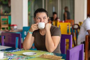 un hombre sentado en una mesa bebiendo una taza de café en Hotel Las Colinas, en Fortuna