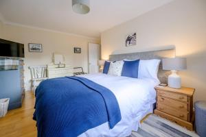 a bedroom with a large bed with a blue blanket on it at Staithe View by Big Skies Cottages in Burnham Deepdale