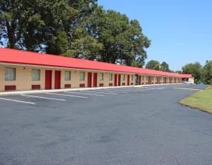 a building with a red roof and a parking lot at Landsford Inn in Fort Lawn