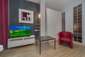 ein Wohnzimmer mit einem TV und einem roten Stuhl in der Unterkunft Saint Michel Quartier Latin in Paris