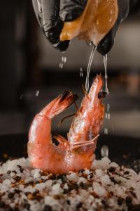 a person is sprinkling sauce on a shrimp at Maritim Marina Bay Resort & Casino Adult Friendly in Vlorë
