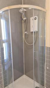 a shower with a glass door in a bathroom at Braillen Suite- 2 bedroom with kitchenette and bathroom in Denbigh