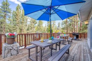 a deck with two picnic tables and a blue umbrella at 068 - White Bear Lodge in Big Bear Lake