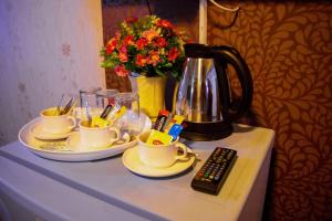 Visiting Card Hotel & Resort في بانكوك: طاولة مع أكواب وقدر قهوة وريموت كنترول