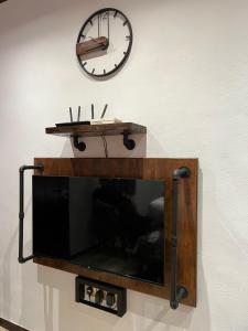 a tv on a wall with a clock on the wall at ZUSCH STUDIO in Pantai Cenang