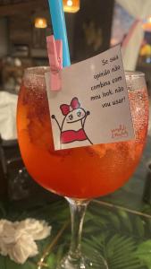 a glass of orange liquid with a sign on it at Pousada Pena in Mucuri