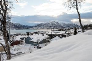 a town covered in snow with a mountain in the background at Modern apartment in the center of the island in Tromsø