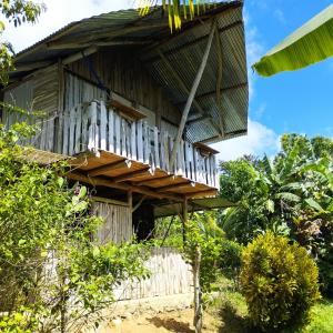 - un bâtiment en bois avec un balcon au-dessus dans l'établissement La Muñequita Lodge 1 - culture & nature experience, à Palmar Norte