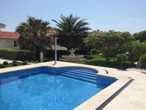 a swimming pool in a yard with a fountain and trees at Apartments Villa Jadranka Adults only in Bol