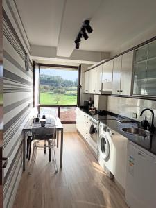 a kitchen with a table and a sink and a dishwasher at Duplex con vistas al Picu Pienzu, Colunga in Colunga