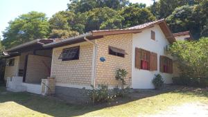 ein kleines gelbes und weißes Haus mit Bäumen in der Unterkunft Morada Caminho do Mar in Praia do Rosa