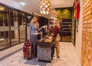 zwei Frauen, die an einer Kasse in einem Laden stehen in der Unterkunft Hotel Libertas elements pure in Freiburg im Breisgau