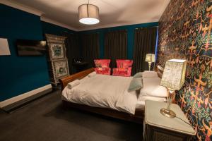 a bedroom with a bed with blue walls and red pillows at The Angel of Bow in London