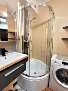 a bathroom with a shower and a sink and a washing machine at Apartament Radiostacja, parking free, klimatyzacja in Gliwice