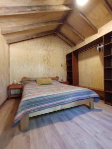 Cama grande en habitación con techo de madera en Habitación Establo de Caballos, en Curarrehue