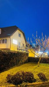 ein gelbes Haus mit einem Baum im Hof in der Unterkunft Patyi Étterem és Hotel in Bögöte