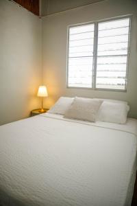 a white bed in a room with a window at John & Marina’s Place in Salinas