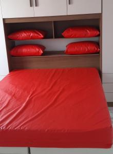 a red bed with red pillows on it at Apartamento encantador com vaga de garagem in Rio de Janeiro