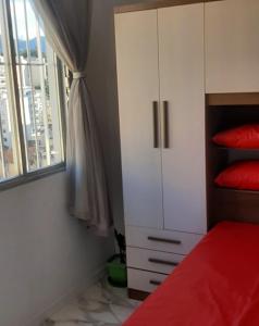 1 dormitorio con cama roja y armario blanco en Apartamento encantador com vaga de garagem, en Río de Janeiro