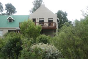 a house with a deck on the side of it at Fijnbosch Cottage and Camping in Stormsrivier