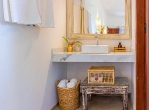 baño con lavabo, mesa y espejo en Pariri Suites, en Trancoso