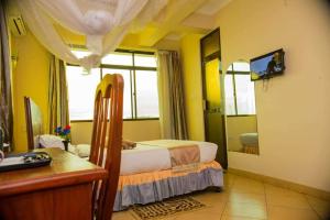 1 dormitorio con cama, escritorio y espejo en Grace Land Hotel, en Arusha
