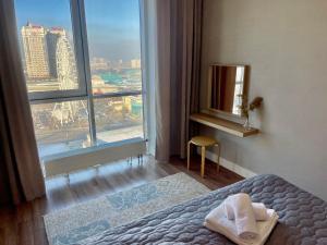 Cette chambre comprend un lit et une grande fenêtre. dans l'établissement Шикарные апартаменты с прекрасным видом в лучшем районе, à Almaty