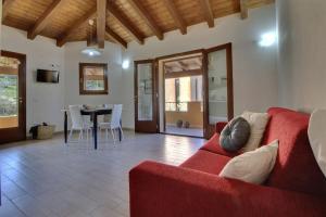 a living room with a red couch and a table at Casa Mediterraneo Lu Bagnu Castelsardo in Castelsardo